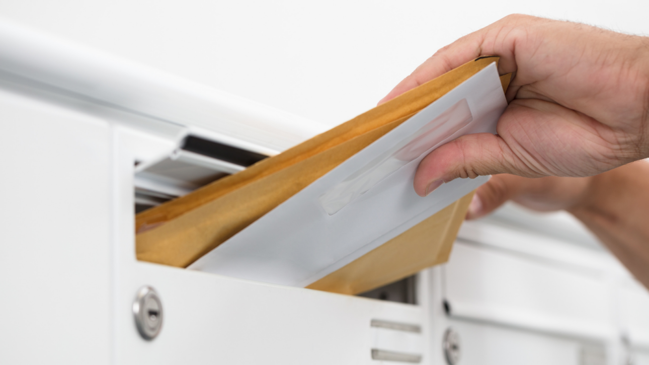 Hand haalt WOZ-beschikking uit brievenbus, ter illustratie van de jaarlijkse waardebepaling van uw woning in 2026