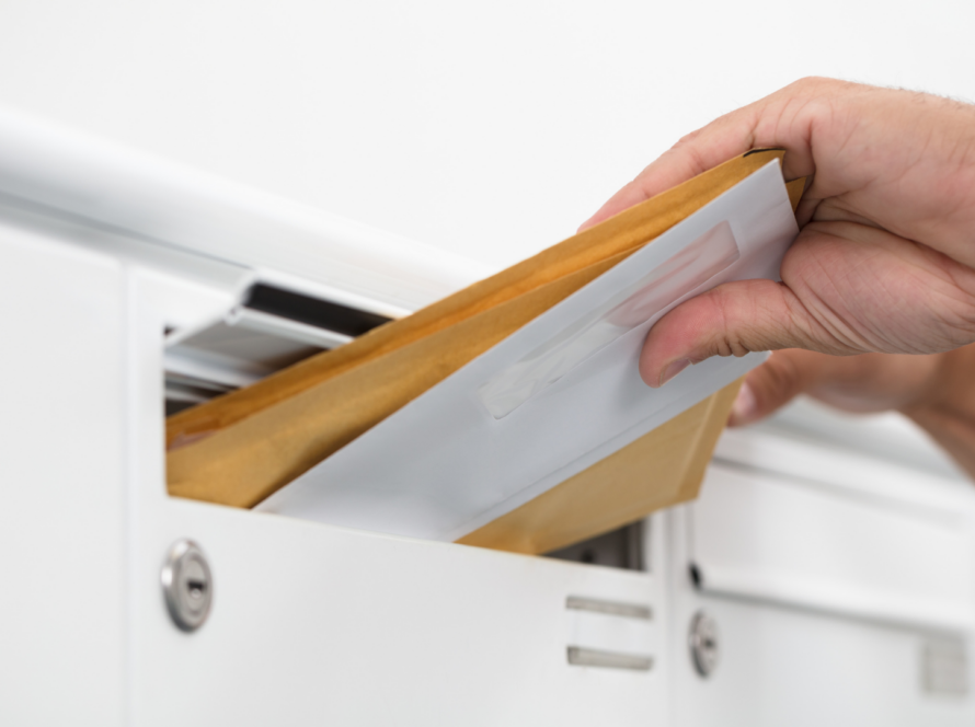 Hand haalt WOZ-beschikking uit brievenbus, ter illustratie van de jaarlijkse waardebepaling van uw woning in 2026