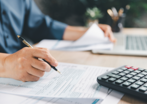 Ondernemer vult btw-aangifte in achter bureau met facturen en calculator als illustratie van veelgemaakte fouten in de btw-aangifte